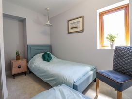 A bedroom with a bed, chair, and window at Trefin in Cemaes Bay