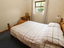 A bedroom with a bed and window at Swallow Cottage Helston