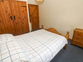 A bedroom with a wooden bed and wardrobe at Swallow Cottage Helston