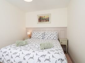 A bedroom with a bed and a painting at Badger Cottage in Driffield
