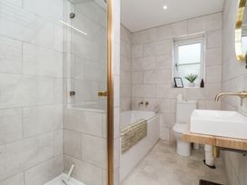 A bathroom with a shower, bathtub, toilet, and sink at Badger Cottage in Driffield