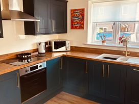A kitchen with appliances and a window at Badger Cottage Wold Newton