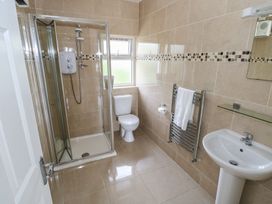 A bathroom with a shower, toilet, sink, and towel rail at Tí Chonaill