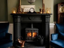 A fireplace with a clock and armchairs in a living room at Chowdene Lodge Estate