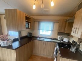 A kitchen with cabinets, sink, stove, kettle, and microwave at 