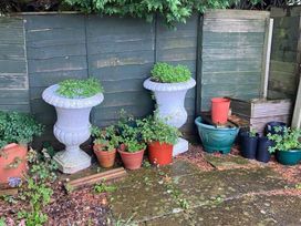 A garden area with plant pots and ornamental urns against a wooden fence