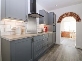A kitchen with gray units and a bricked archway at Seaside Bungalow in Rhyl