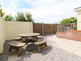 An outdoor seating area with a round table and benches at Seaside Bungalow in Rhyl