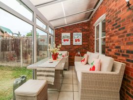 A conservatory with seating arrangement and a dining table at Robins Nest in Rhyl
