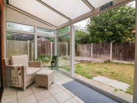 A conservatory with seating area and garden view at Robins Nest in Rhyl