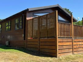 A wooden house with a deck and fence at Lakeside Retreat in Newton Abbot