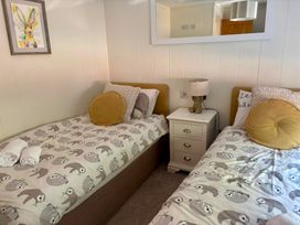 A bedroom with two beds and a nightstand at Lakeside Retreat in Newton Abbot