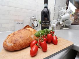 A kitchen scene with bread, wine, glasses and tomatoes at Owl in Pickering