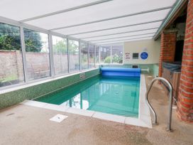 An indoor swimming pool with a pool cover and a hot tub at Owl in Pickering