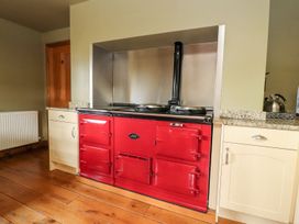 A kitchen with a red range cooker and wooden flooring at Shepherd's Barn in Lancaster