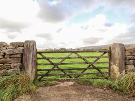 A wooden gate in a stone wall with grass and clouds at Shepherd's Barn in Lancaster