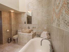 A bathroom with a bathtub, a toilet, and a stone sink at Shepherd's Barn in Lancaster