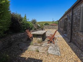 An outdoor patio with a stone table and wooden chairs at Shepherd's Barn in Lancaster