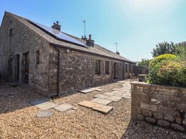 An outdoor view of a stone building with solar panels and a gravel pathway at Shepherd's Barn Lancaster