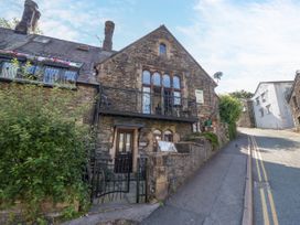 A stone building with a balcony and door at Hillside Cottage in Bowness-On-Windermere