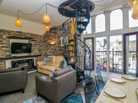 A living room with a sofa and spiral staircase at Hillside Cottage Bowness-On-Windermere
