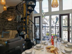 A dining room with a spiral staircase and a dining table at Hillside Cottage in Bowness-On-Windermere