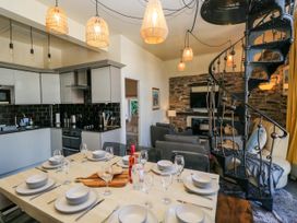 A dining room with a kitchen and spiral staircase at Hillside Cottage in Bowness-On-Windermere