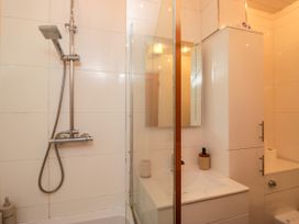 A bathroom with a shower, sink, mirror, and toilet at Hillside Cottage Bowness-On-Windermere