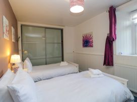A bedroom with two beds and a sliding door at Hillside Cottage Bowness-On-Windermere