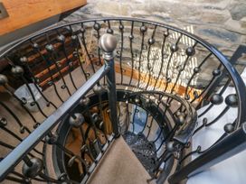 A spiral staircase with a handrail and stone wall at Hillside Cottage Bowness-On-Windermere