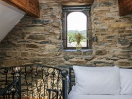 A bedroom with a stone wall and a window at Hillside Cottage in Bowness-On-Windermere