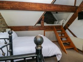A bedroom with a bed and stairs leading to a loft area at Hillside Cottage in Bowness-On-Windermere