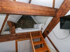 A loft with a bed and stairs at Hillside Cottage in Bowness-On-Windermere