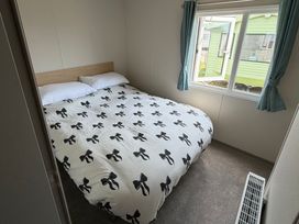 A bedroom with a double bed and a window at Trecco Bay Holiday Park - Magnolia 11 Porthcawl