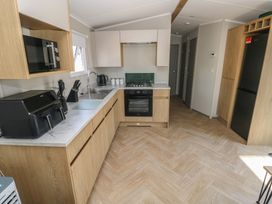 A kitchen with cabinets and appliances at Trecco Bay Holiday Park - Magnolia 11 Porthcawl