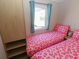 A bedroom with two beds and a wardrobe at Trecco Bay Holiday Park - Magnolia 11, Porthcawl