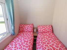 A bedroom with two beds and a lamp at Trecco Bay Holiday Park - Magnolia 11, Porthcawl