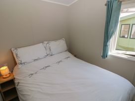 A bedroom with a double bed and bedside lamp at Trecco Bay Holiday Park - Magnolia 11, Porthcawl