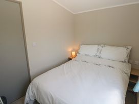A bedroom with a bed and nightstand at Trecco Bay Holiday Park - Magnolia 11, Porthcawl
