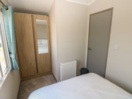 A bedroom with a bed, wardrobe, and radiator at Trecco Bay Holiday Park - Magnolia 11, Porthcawl