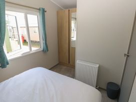 A bedroom with a bed and wardrobe at Trecco Bay Holiday Park - Magnolia 11 Porthcawl