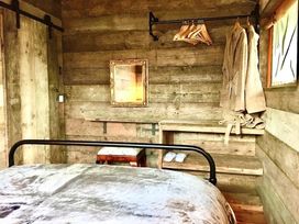 A bedroom with a bed, mirror, and clothing hangers in a wooden cabin