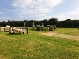 A garden with tables and chairs surrounded by plants and a fence