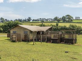 A tent structure with a wooden deck and deer in an outdoor area at Luxury Safari Lodge Sleeps 4/6 Deer Park Dogs Ok Zeal Monachorum near Bow