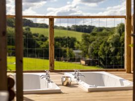 Two bathtubs on a deck overlooking fields at a property