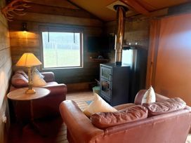 A living room with sofas and a wood stove in a cabin