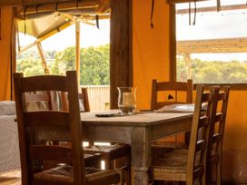A dining table with chairs and a candle at a tent in a rural area