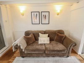 A living room with a sofa, wall art, and a radiator at Pax Cottage