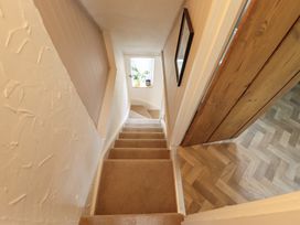 A staircase leading down to a hallway with a window and a door at Pax Cottage