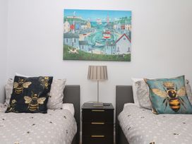 A bedroom with two beds, pillows, a lamp, and wall art at 3 Heath Park Brixham